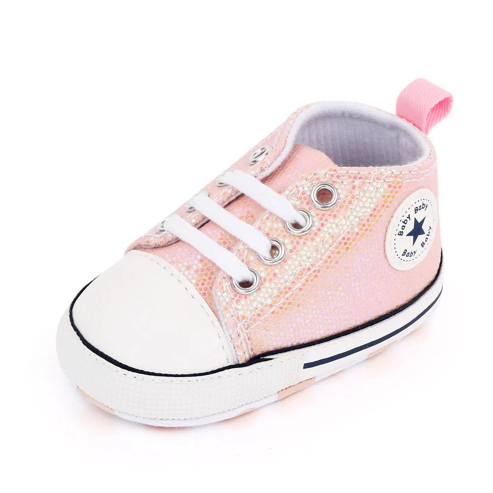 Close-up of white shoelaces and sequin texture on baby girls' canvas walking shoes