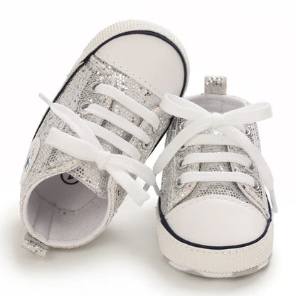 Close-up of pink sequin detail on baby girls' canvas first walking shoes with white laces