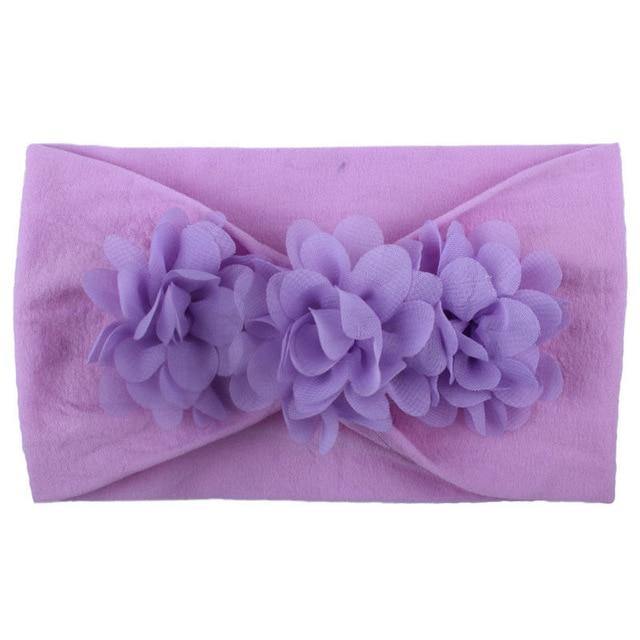 Side profile of a baby girl wearing a soft elastic floral headband, showcasing its gentle fit.