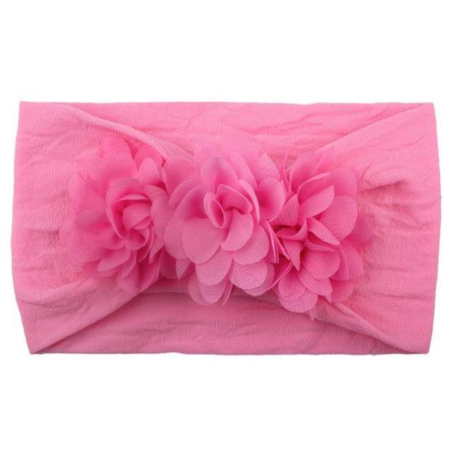 Hanging display of various soft elastic flower headbands for baby girls, ready for purchase.