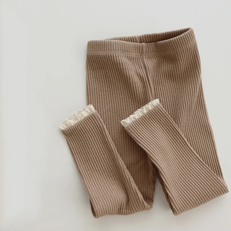 Close-up of the ribbed texture on baby girls' soft cotton leggings in a neutral color.