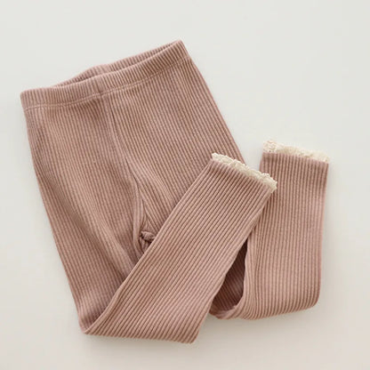 Baby girl modeling comfortable ribbed cotton leggings, suitable for all seasons.