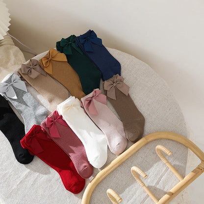 Baby girl's knee-high socks with bows folded neatly, ready for a clothing display