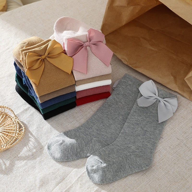 Stylish baby accessories: pink knee-high socks with large satin bows, side view