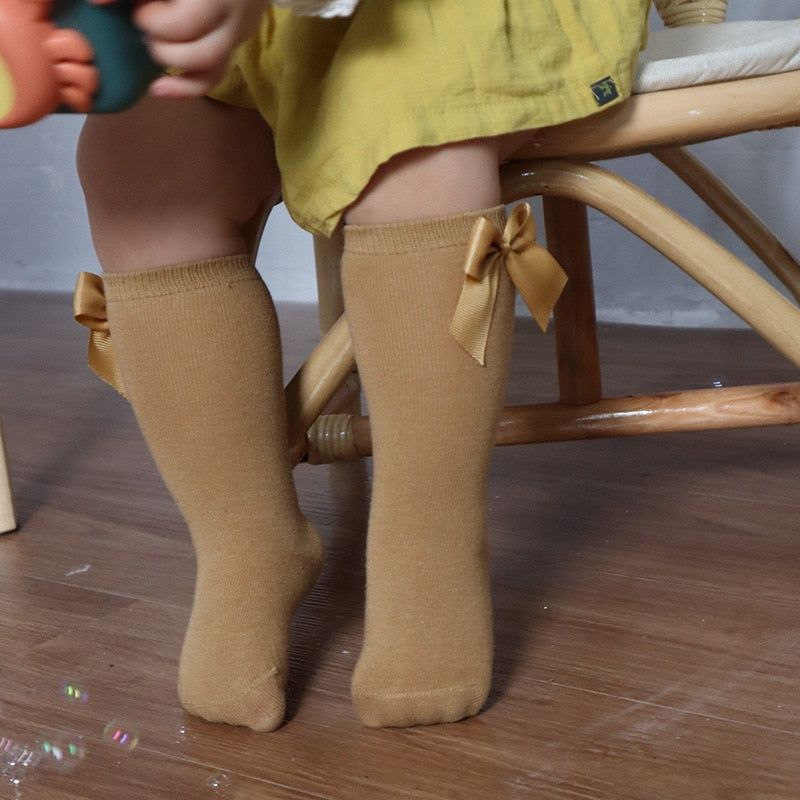 Cute baby clothing: white knee-high socks with a double satin bow on the back