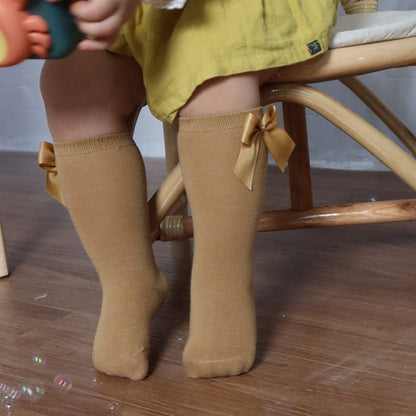 Cute baby clothing: white knee-high socks with a double satin bow on the back