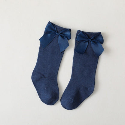 Cute pink knee-high baby socks with delicate white bows, soft cotton for girls