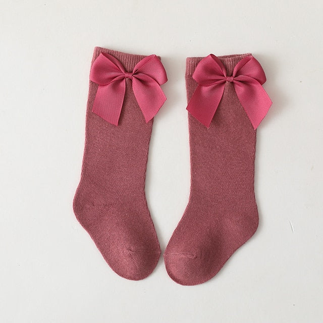 Toddler girl's blue knee-high socks featuring charming satin bows and ruffled trim