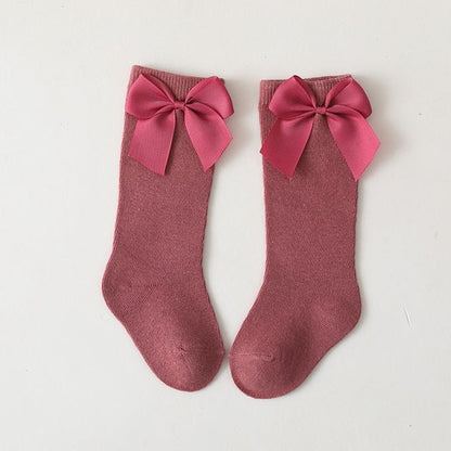 Toddler girl's blue knee-high socks featuring charming satin bows and ruffled trim