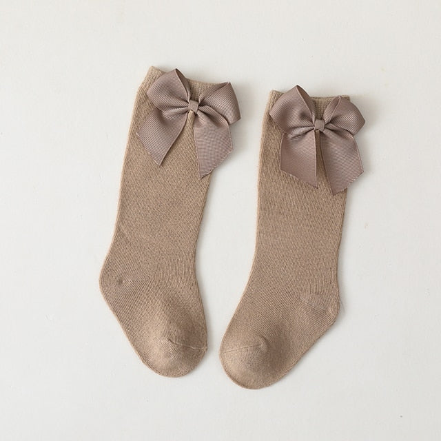 Anti-slip knee-high cotton socks in white for baby girls, featuring sweet attached bows