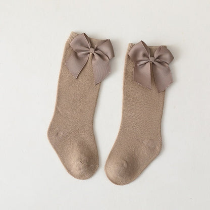 Anti-slip knee-high cotton socks in white for baby girls, featuring sweet attached bows