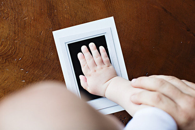 White frame baby keepsake kit with impressions of a baby's hand and foot