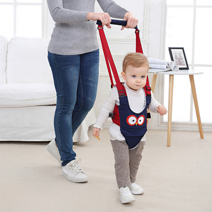 Baby in a blue walking harness with yellow straps, taking first steps with an adult's help.