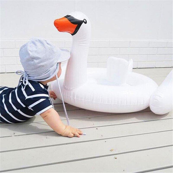 Toddler enjoying summer fun in an infant white swan swim ring pool toy