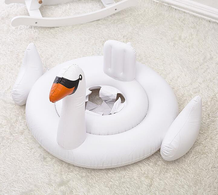 Happy baby in a white swan swim ring, ensuring water safety during play