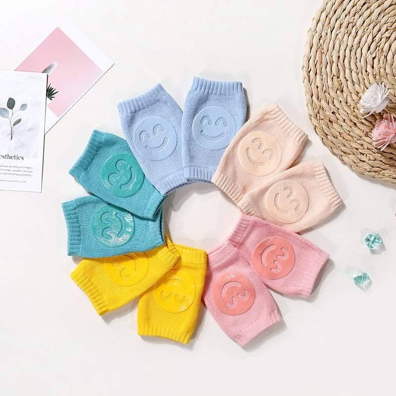 Collection of colorful baby crawling knee pads: blue, pink, grey, for toddler safety.
