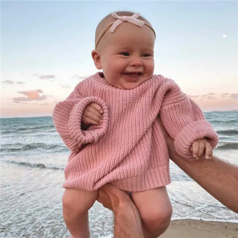 Stylish baby wearing a cream knitted top with jeans, a cute and casual outfit.