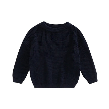 Adorable baby in a grey knitted sweater smiling, cozy and stylish infant apparel.