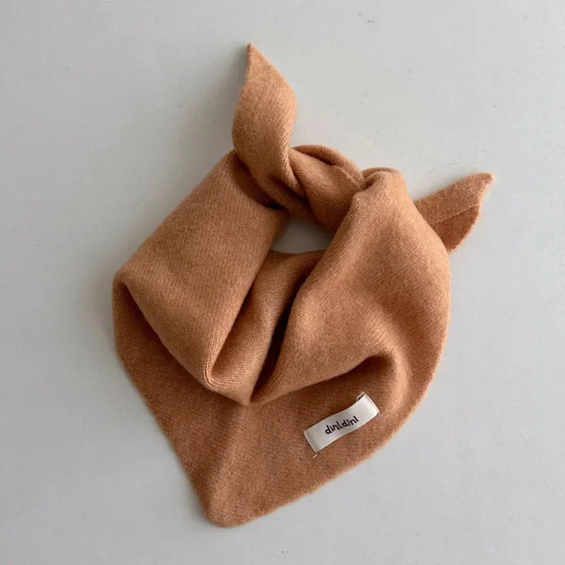 Stack of colorful knitted baby triangle scarves, soft and warm winter accessories.