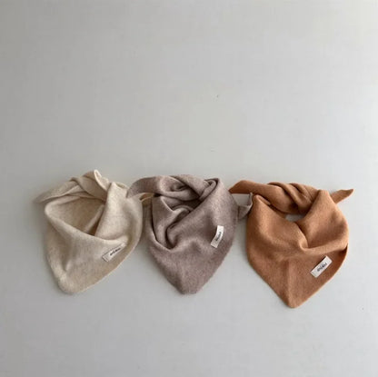 Close-up of a knitted baby triangle scarf, soft texture, ideal for infant winter fashion.