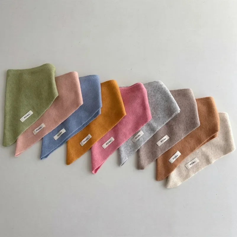 Toddler wearing a soft knitted triangle scarf, warm cashmere-feel, outdoor winter gear.