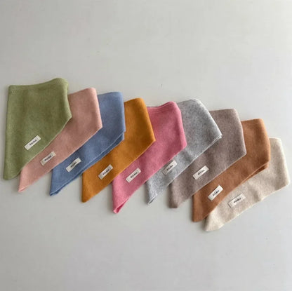 Toddler wearing a soft knitted triangle scarf, warm cashmere-feel, outdoor winter gear.