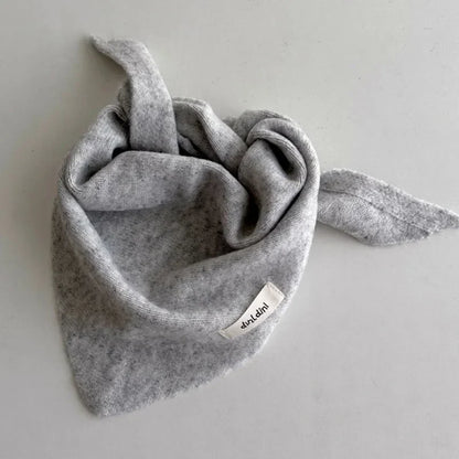 Child modeling a soft knitted triangle scarf, cozy and fashionable winter accessory.