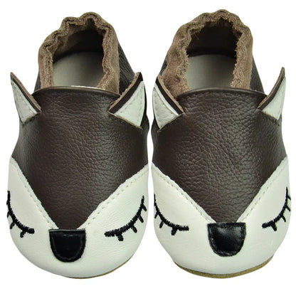 A baby wearing tan leather soft sole moccasins while crawling on a rug