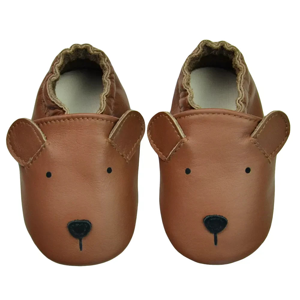 Tan genuine leather baby moccasins on a wooden surface, highlighting the texture