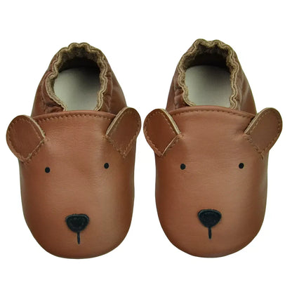 Tan genuine leather baby moccasins on a wooden surface, highlighting the texture