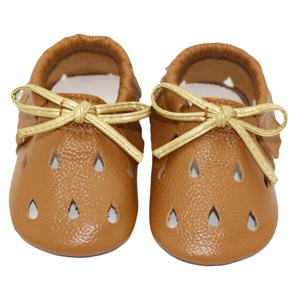 Close-up of the stitching and soft texture of a brown leather baby moccasin
