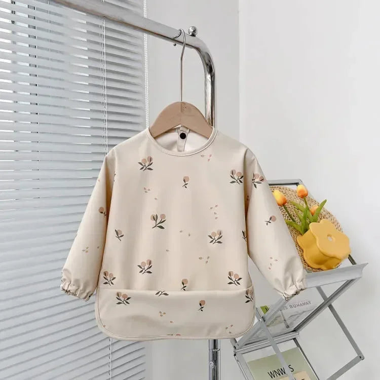 Cute baby long sleeve waterproof bib folded neatly, showcasing its compact design for travel
