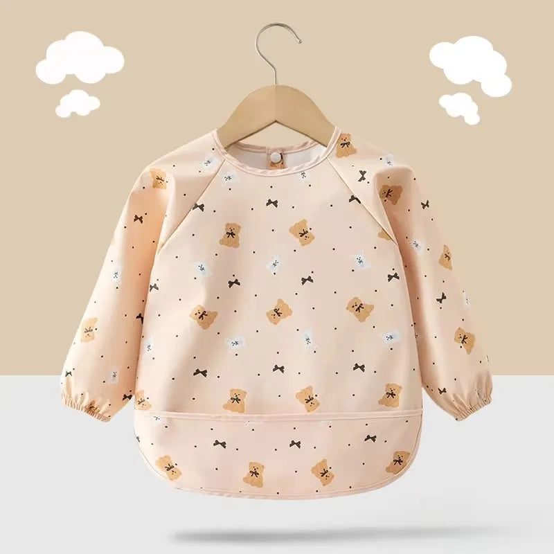 Baby wearing a green long sleeve art smock bib with food, highlighting its protective features