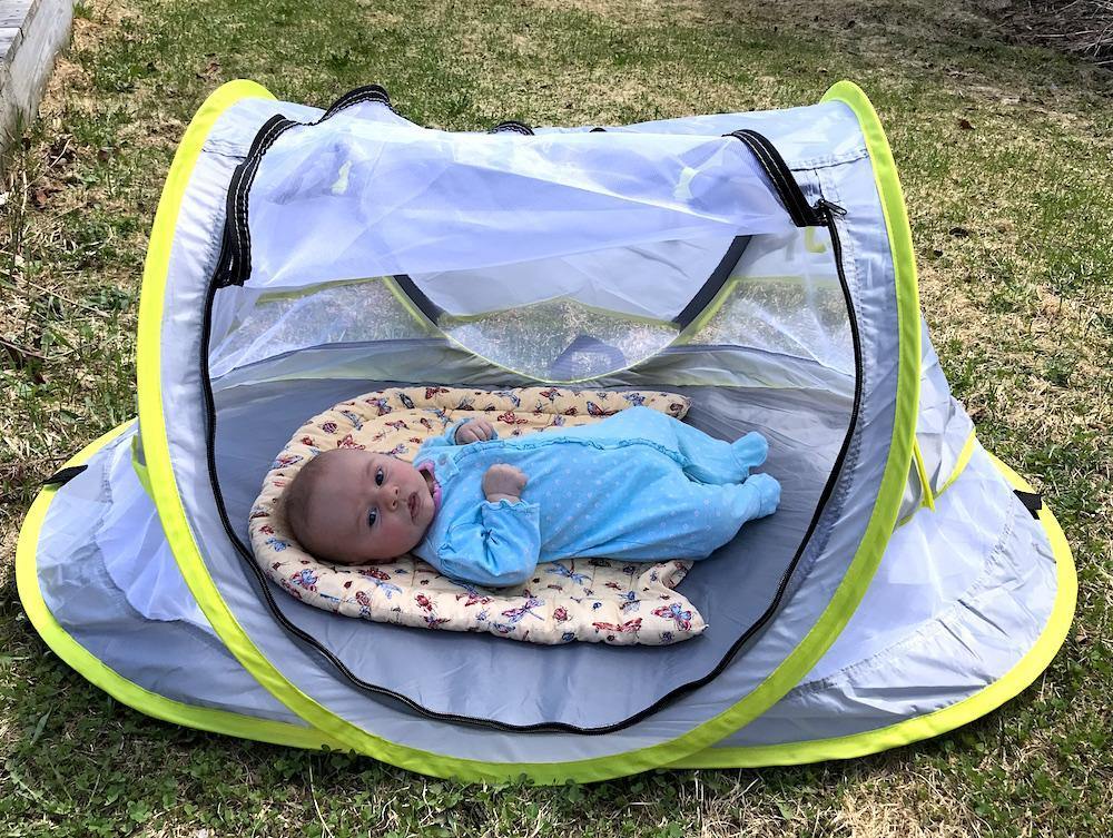 Baby outdoor pop-up net tent provides sun and insect protection with a portable design.