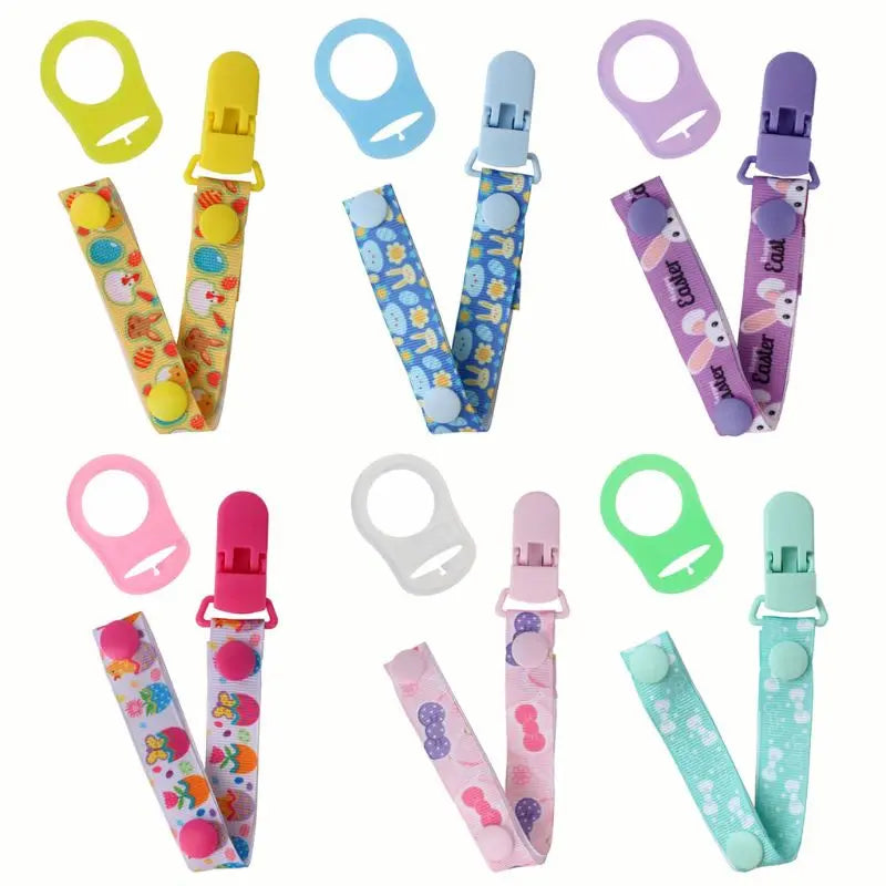 Three colorful pacifier clips in blue, green, and yellow with MAM ring adapters, baby essentials.