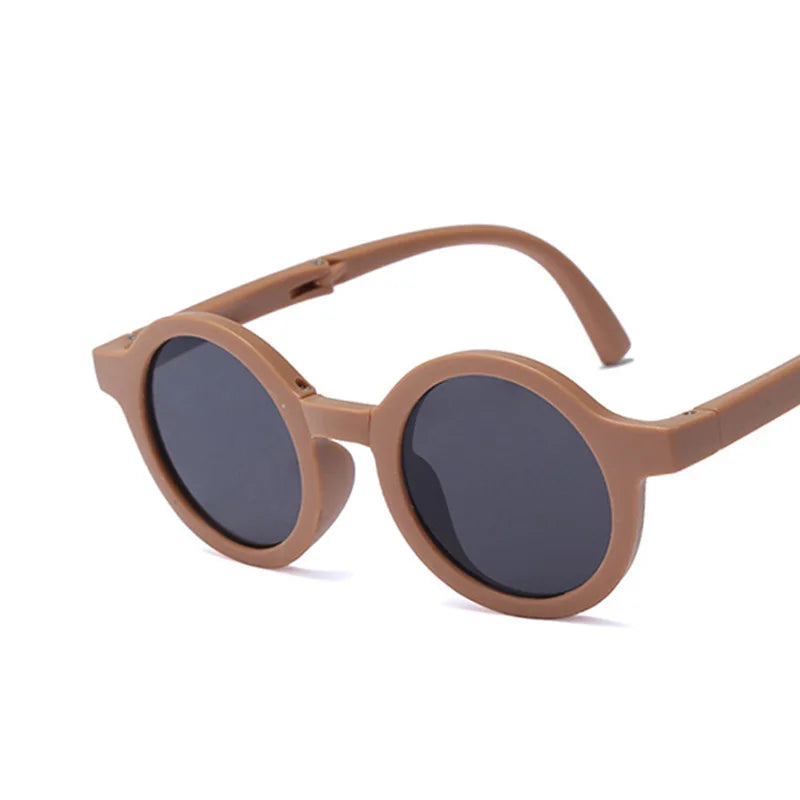 Infant wearing beige retro foldable round sunglasses, looking cute and protected from sun