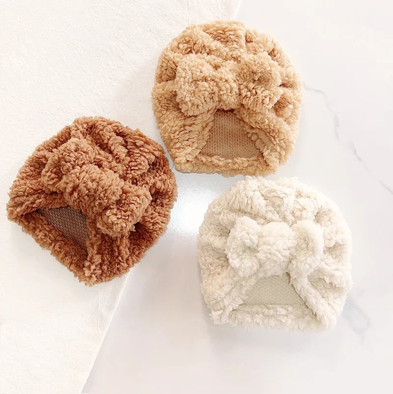 Baby's cozy knitted beanie hat in soft cream, perfect for winter warmth and comfort.