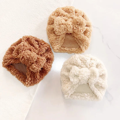 Baby's cozy knitted beanie hat in soft cream, perfect for winter warmth and comfort.