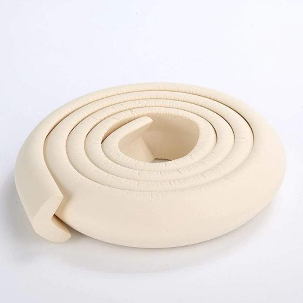 Close-up of white foam baby safety corner protector installed on a table edge.
