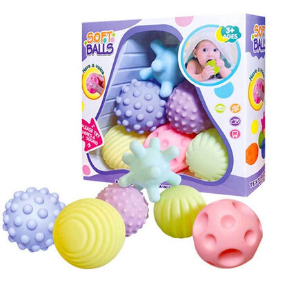 Baby reaching for brightly colored, textured sensory balls, great for infant development