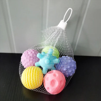 Smiling baby holding a textured rubber grip ball, enjoying bathtime play