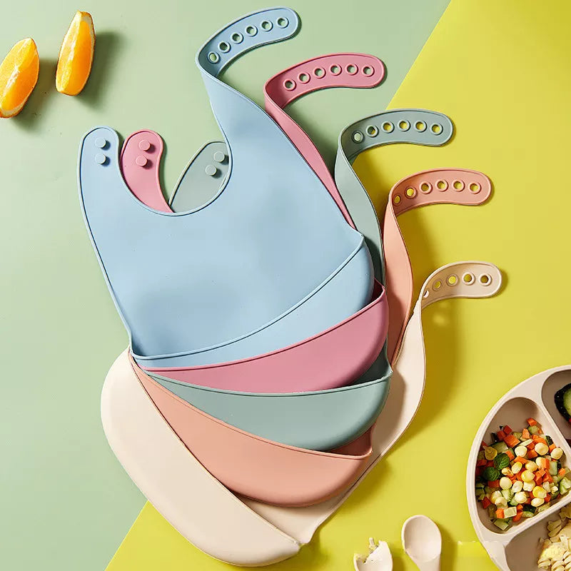 Baby silicone bib, adjustable snaps, solid pink, waterproof, for mess-free meals.