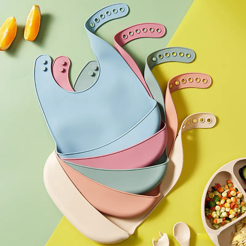 Flexible silicone bib with adjustable snaps for babies, prevents food stains.