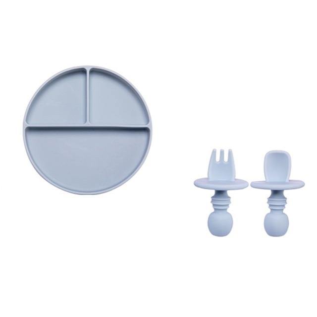 Silicone baby plate with built-in dividers, accompanied by a small fork and spoon for toddlers