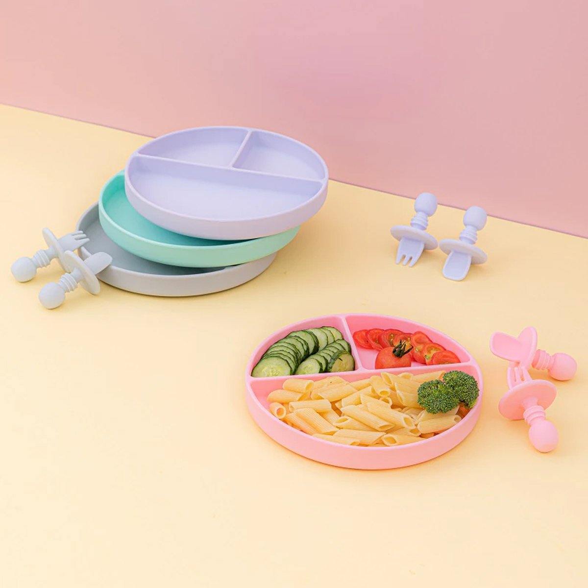Close-up of a baby silicone divided plate showing sections for different foods, with fork & spoon