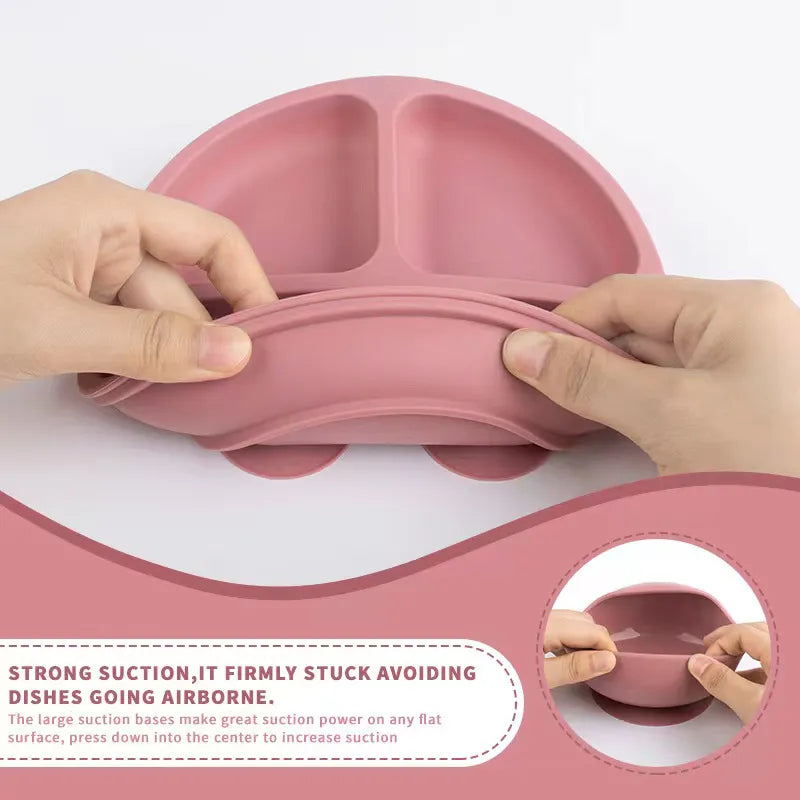 Close-up of pink baby silicone divided plate for infant feeding with matching soft tip spoon