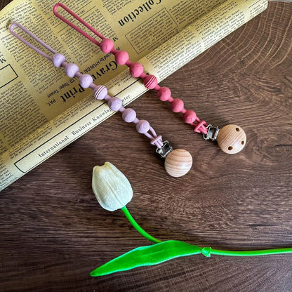 Reliable pacifier holder: silicone clip with an attached teether for infant teething relief.