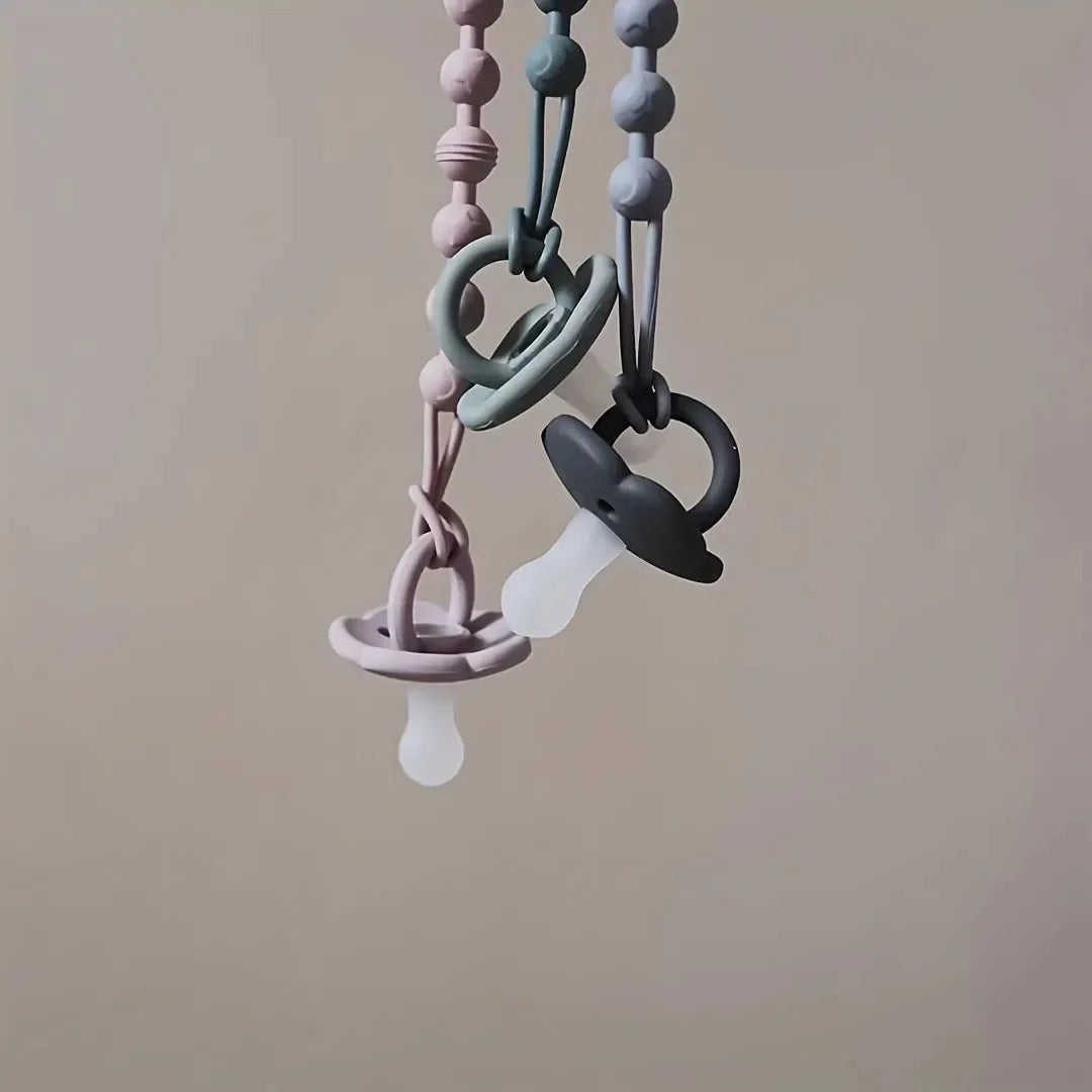 Newborn essentials: white silicone pacifier holder with integrated teether for soothing gums.