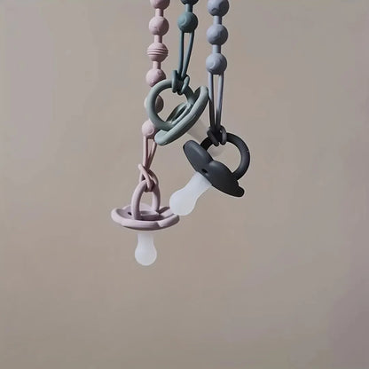 Newborn essentials: white silicone pacifier holder with integrated teether for soothing gums.