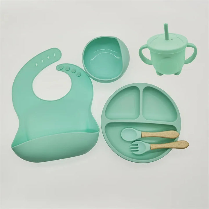 Weaning set for babies: silicone suction plate, bowl, bib, and ergonomic toddler utensils.